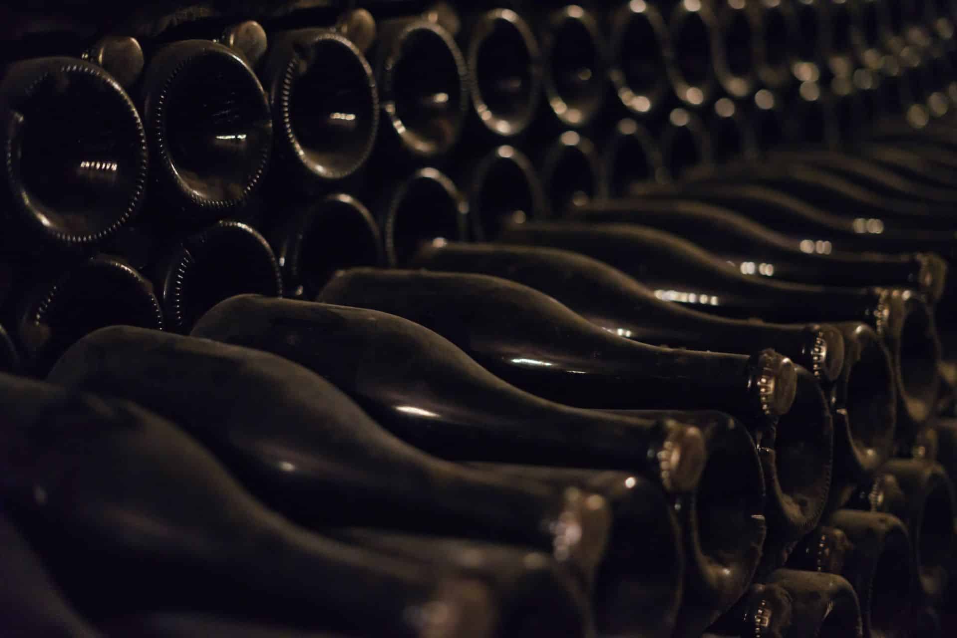 Sticle de vin și de șampanie păstrate culcate într-o pivniță de maturare