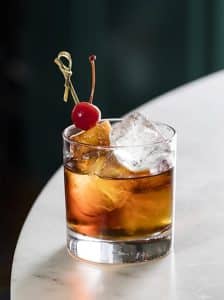 Cocktail Old Fashioned cu bourbon, cub de gheață și coajă de portocală